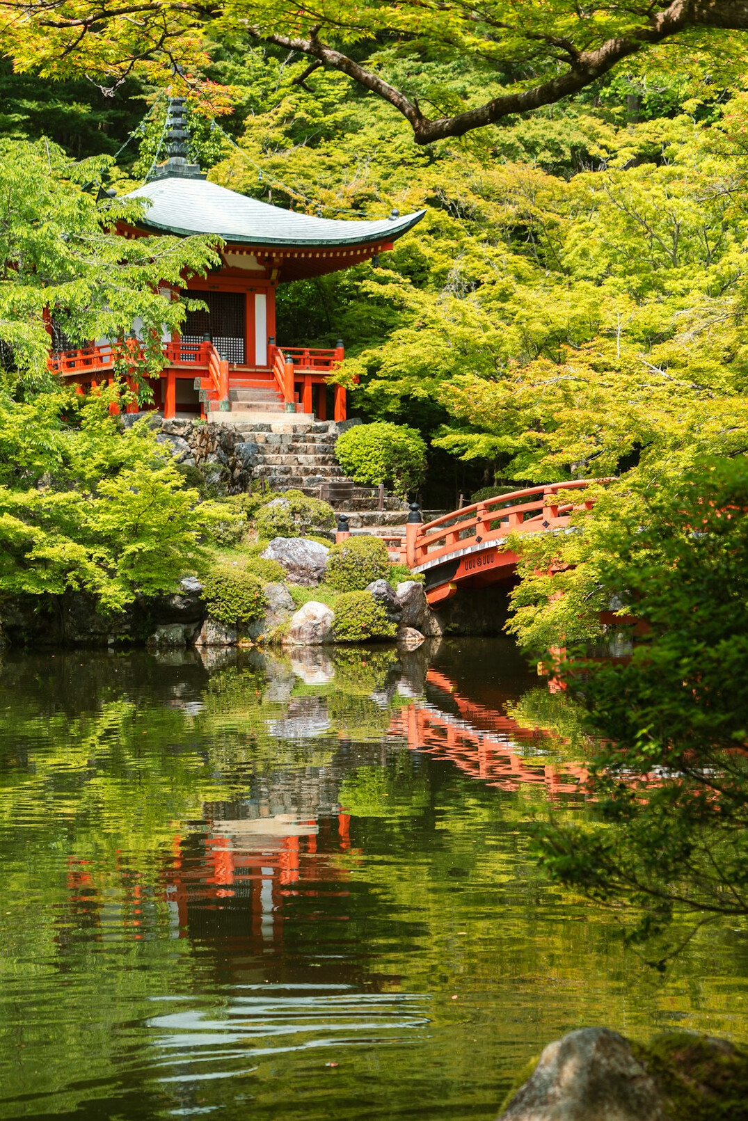 Japanese temple surrounded by vibrant autumn foliage by a lake